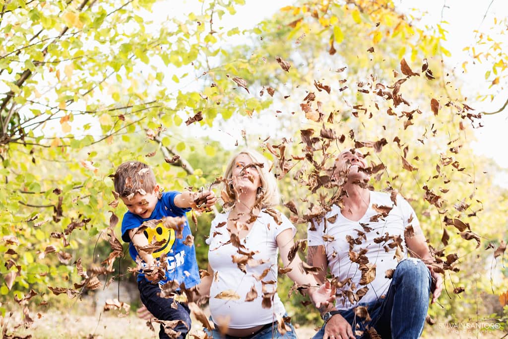 Exemple photo d'une séance grossesse en famille dans jardin avec feuilles mortes d'automne